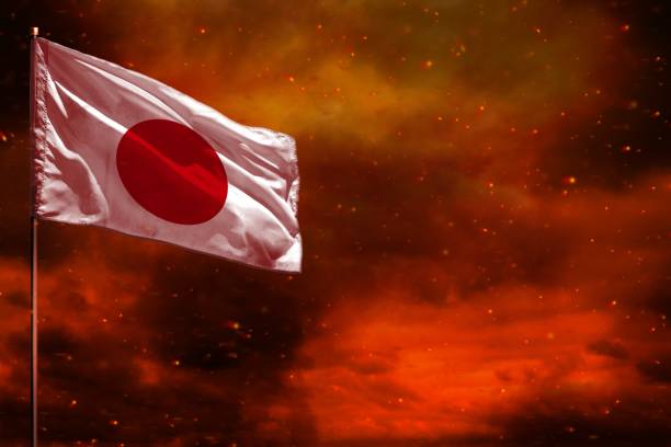 istock Fluttering Japan flag mockup with blank space for your text on crimson red sky with smoke pillars background. Troubles concept. 1049677050