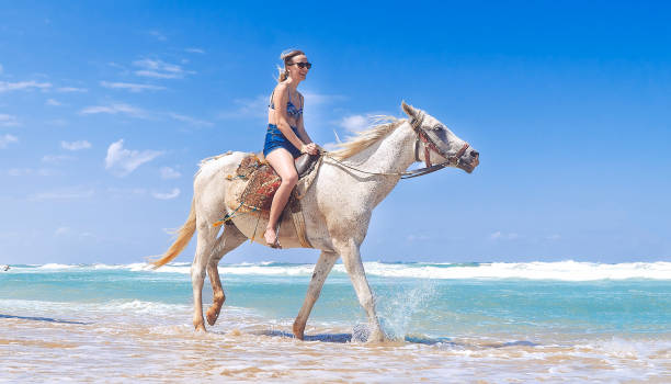 Woman riding a white horse on the beach
