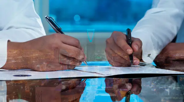 Businessmen hands signing documents on Riyadh skyline cityscape background multi exposure