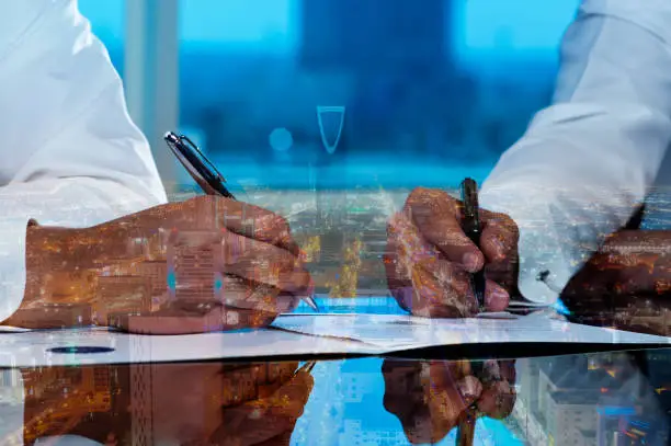 Businessmen hands signing documents on Riyadh skyline cityscape background multi exposure
