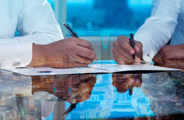 Businessmen hands signing documents on Riyadh skyline cityscape background multi stock photo