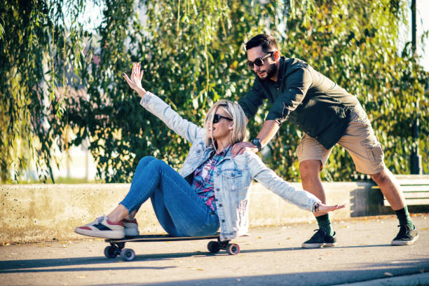 istock Young man pushing his girlfriend on skateboard 1049694408