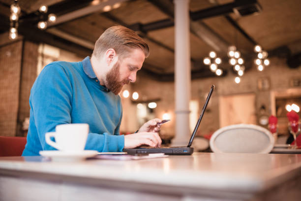 istock Young, redhead businessman, on coffee break using laptop, shopping online 1049697538