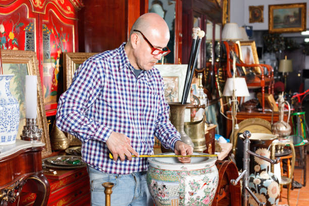 istock Experienced appraiser of antiques shop measuring antique vase while determining value 1049697582