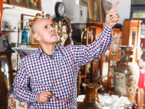 istock Man pointing at goods at antiques shop 1049697620