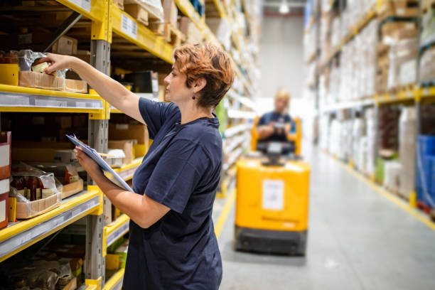 Woman checking packages on warehouse racks stock photo