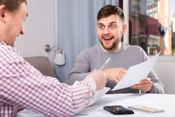 istock Happy man discussing papers with male colleague 1049698368
