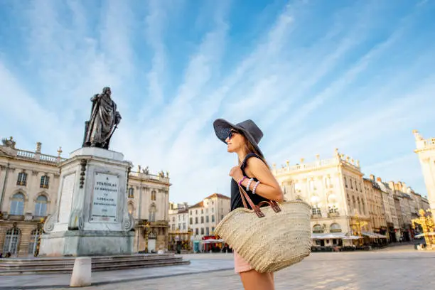 Young woman tourist enjoying beautiful morning view on the central square traveling in Nancy city in France