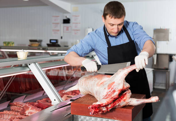 istock butcher cutting lamb carcass in butcher shop 1049700838