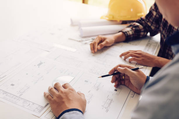 istock Architects working with blueprints and discussing project together at the meeting in the office. 1049701636