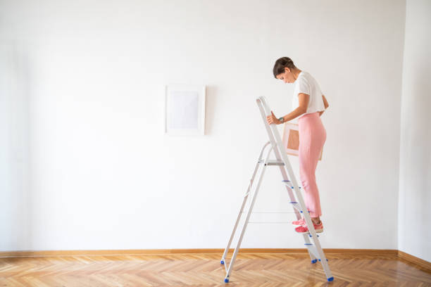 istock Woman with picture frame standing on the ladder 1049707626