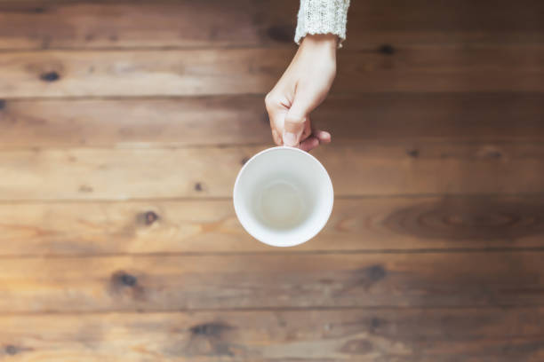 istock A girl hands with an empty cup for coffee on the wooden table background. 1049708040