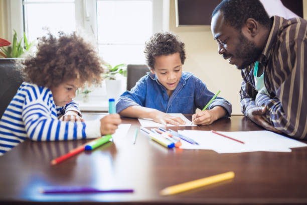 istock Kids having spending time with their father at home. They are doing homework 1049708076