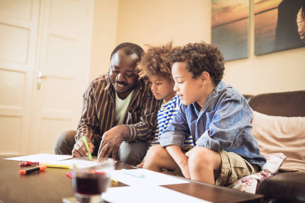 istock Kids having spending time with their father at home. They are doing homework 1049708124