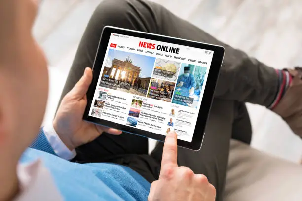 Photo of Man reading daily news online on tablet