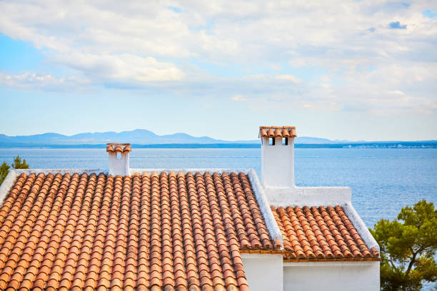 Old ceramic tile roof with seascape in background, Mallorca, Spain.