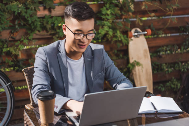 istock smiling asian businessman remote working on laptop in cafe 1049728434