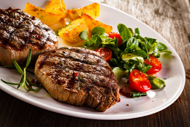 istock Grilled beefsteak, baked potatoes and vegetables on white background 1049732488