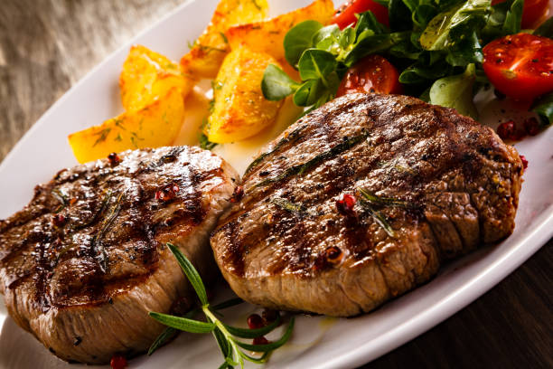 istock Grilled beefsteak, baked potatoes and vegetables on white background 1049732660
