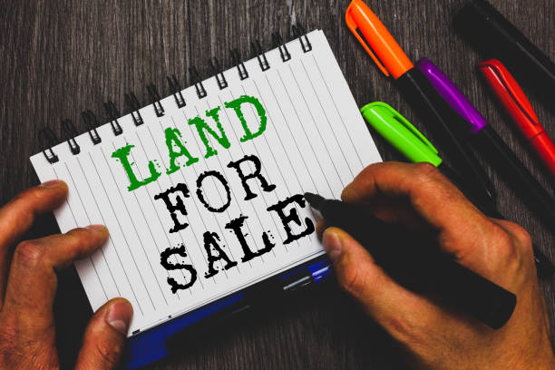 istock Handwriting text writing Land For Sale. Concept meaning Real Estate Lot Selling Developers Realtors Investment Man holding marker notebook paper communicating ideas Wooden background. 1049736260