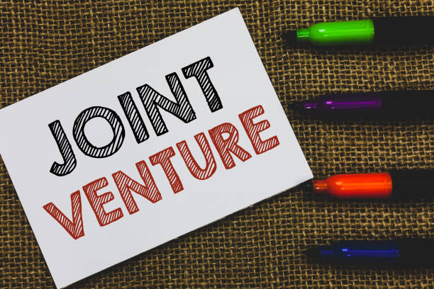 istock Handwriting text Joint Venture. Concept meaning Collaboration Arrangement Parties Partnership Team White Paper Important reminder Communicate ideas Markers Jute background. 1049736924
