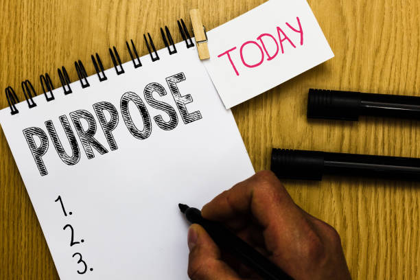 istock Writing note showing Purpose. Business photo showcasing Reason for doing something Desired Goal Target Planned Achievement Man holding marker notebook clothepin reminder wooden table cup coffee. 1049737178