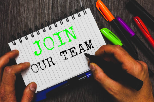 istock Handwriting text writing Join Our Team. Concept meaning Allied Associate Work with us New Employee Hired Enlist Man holding marker notebook paper communicating ideas Wooden background. 1049738630