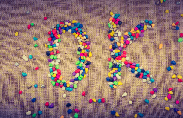 Colorful pebbles form the word OK on canvas ground