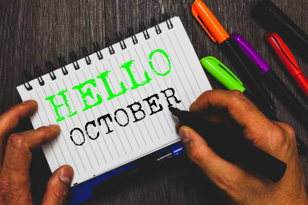 istock Handwriting text writing Hello October. Concept meaning Last Quarter Tenth Month 30days Season Greeting Man holding marker notebook paper communicating ideas Wooden background. 1049741516