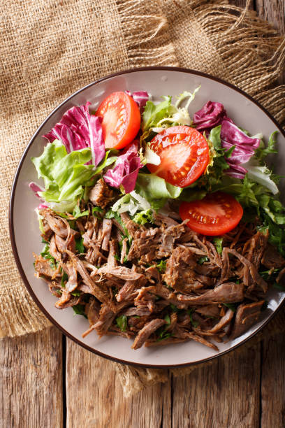 istock Healthy lunch: tender beef with vegetable salad close-up on a plate. Vertical top view from above 1049743174
