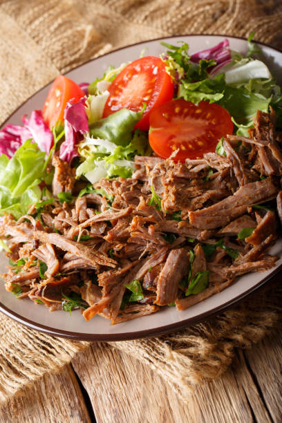 istock Slowly cooked beef with fresh vegetable salad close-up on a table. vertical 1049743220