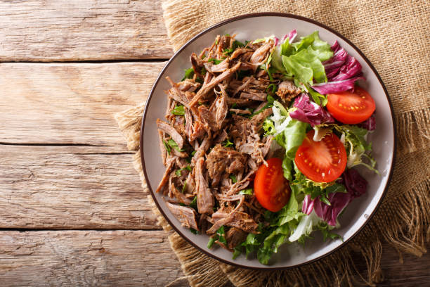 istock Delicious food: slow cooked pulled beef with fresh vegetable salad close-up. Horizontal top view from above 1049745508