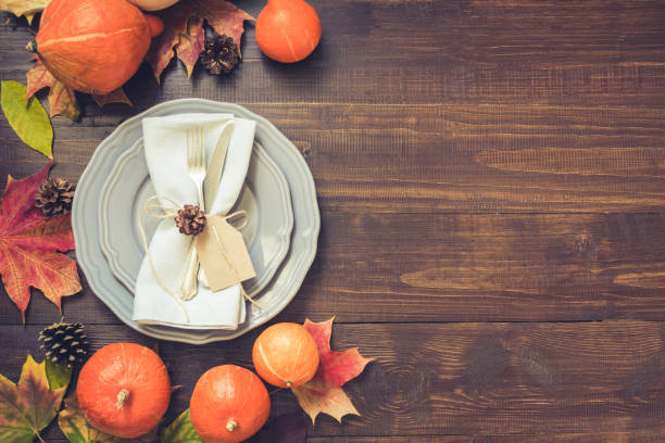 cenário de mesa outono e o dia de ação de graças com folhas caídas, abóboras, especiarias, placa cinza e talheres na mesa de madeira marrom. vista superior, imagem enfraquecida. - thanksgiving table setting autumn - fotografias e filmes do acervo