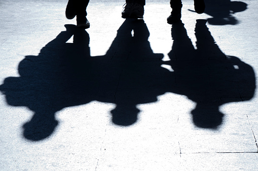 Blurry silhouettes and shadows of three man walking city street in the night