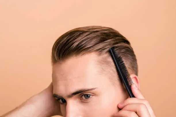Profile side view cropped photo of young handsome man stylist make modern hairstyle, hairdresser isolated on pastel beige background