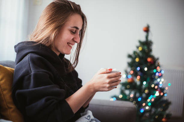 istock Young woman drinking hot chocolate by the Christmas tree 1049751676