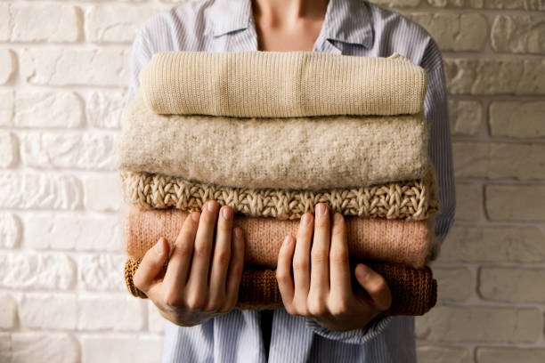 Minimalistic rustic composition with stacked vintage knitted easy chic oversized style sweaters, knitwear outfit. stock photo