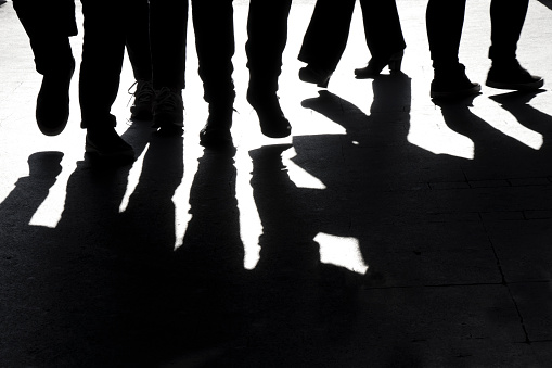 High contrast blurry silhouettes and shadows of legs of  people walking