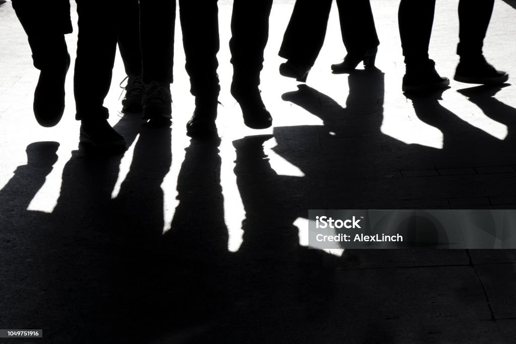 Blurry high contrast silhouettes and shadows of legs High contrast blurry silhouettes and shadows of legs of  people walking Group Of People Stock Photo