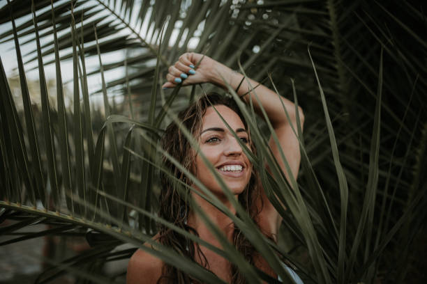 istock Young woman portrait by a palm tree 1049751972