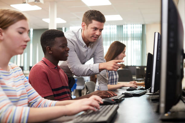 nauczyciel pomaga mężczyzna liceum uczeń pracujący w klasie komputerowej - teacher computer high school student classroom zdjęcia i obrazy z banku zdjęć