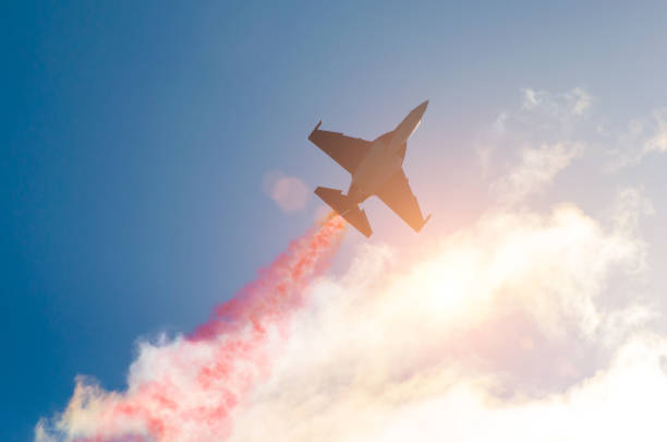 Fighter jet planes fly and leave behind a smoke trail, clouds sun glare