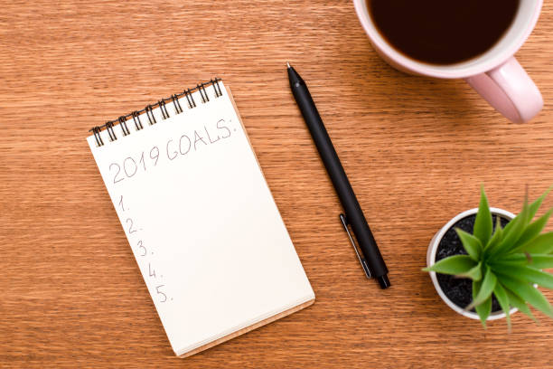 istock Top view 2019 goals list with notebook, cup of coffee on wooden 1049765568