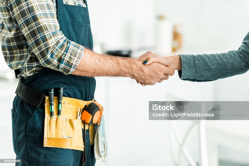 Cropped image de plombier et mains tremblante client dans cuisine - Photo de Plombier libre de droits