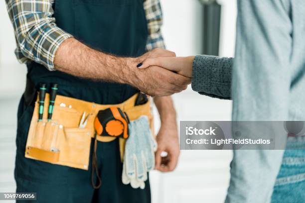 Cropped Image Of Plumber And Customer Shaking Hands In Kitchen Stock Photo - Download Image Now