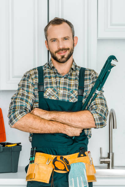 istock handsome plumber holding monkey wrench and looking at camera in kitchen 1049769068