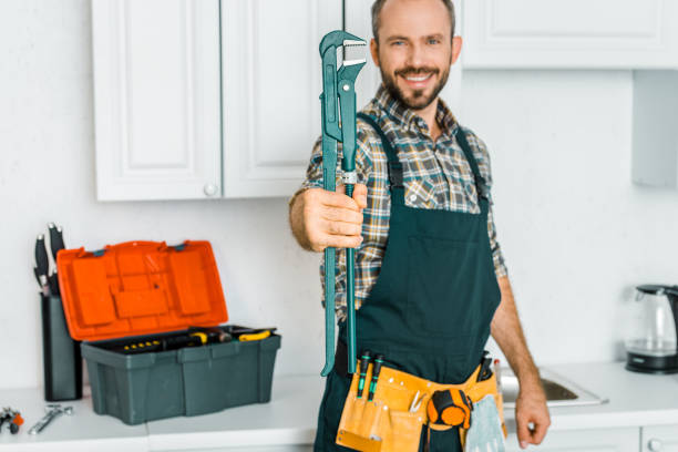 istock smiling handsome plumber showing monkey wrench in kitchen 1049769186