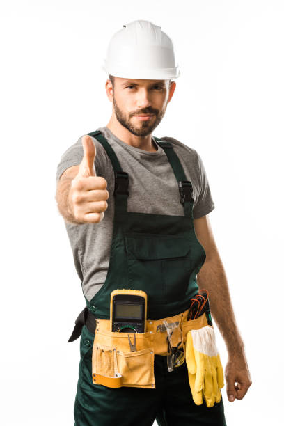 handsome electrician showing thumb up and looking at camera isolated on white