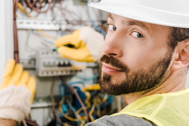 istock handsome bearded electrician repairing electrical box, using screwdriver in corridor and looking at camera 1049770658