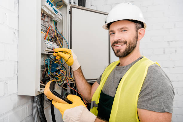 istock smiling handsome electrician checking electrical box with multimetr in corridor and looking at camera 1049771392